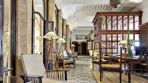 A lobby with a patterned floor, wooden furniture, and a large window with a view. - Heure Bleue Palais (Essaouira)