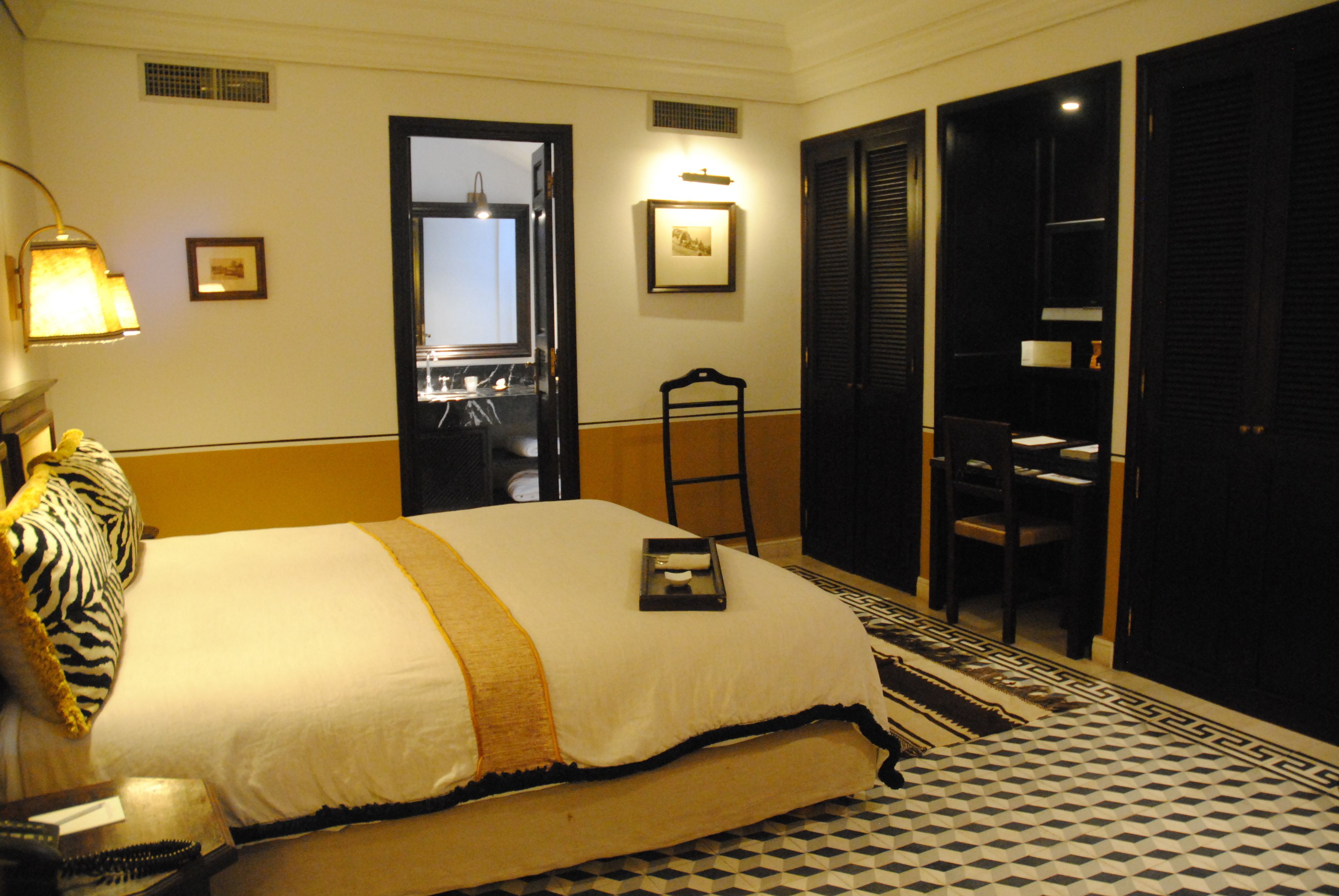 A hotel room with a large bed, a desk, a chair, and a wardrobe.