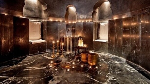 A luxurious bathroom with marble floors, a central sink, and multiple candles. - Heure Bleue Palais (Essaouira)