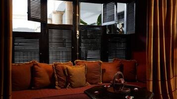 A room with a sofa, a table with a tray, and a window with shutters.
