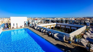A rooftop pool area with a clear view of the cityscape in the background. - Heure Bleue Palais (Essaouira)
