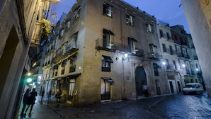 A narrow street with buildings on either side, a cobblestone road, and a few people walking. - Hotel Boutique Alicante Palacete S.XVII - Adults Only (Alicante)
