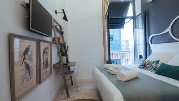 Ein Hotelzimmer mit Bett, Fernseher, Schreibtisch und Balkonblick.