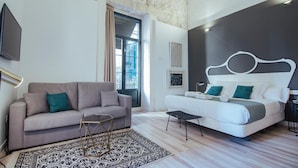 A modern bedroom with a bed, a sofa, a coffee table, and a patterned rug. - Hotel Boutique Alicante Palacete S.XVII - Adults Only (Alicante)