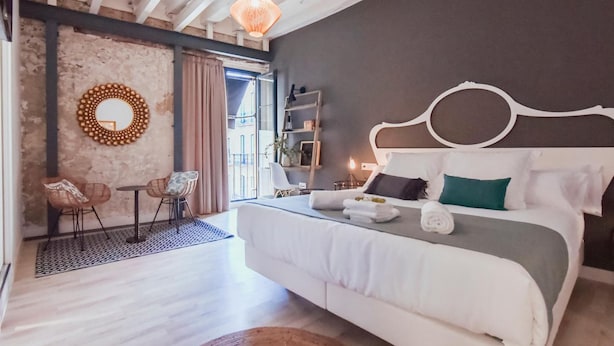 A modern bedroom with a large bed, a round mirror, and a dining area with chairs. - Hotel Boutique Alicante Palacete S.XVII - Adults Only (Alicante)