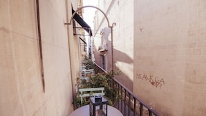 A narrow alleyway with a round table and a lantern, a green bench, and a wall with graffiti. - Hotel Boutique Alicante Palacete S.XVII - Adults Only (Alicante)