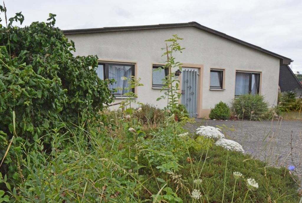 A single-story building with a flat roof, three windows, and a gravel driveway.