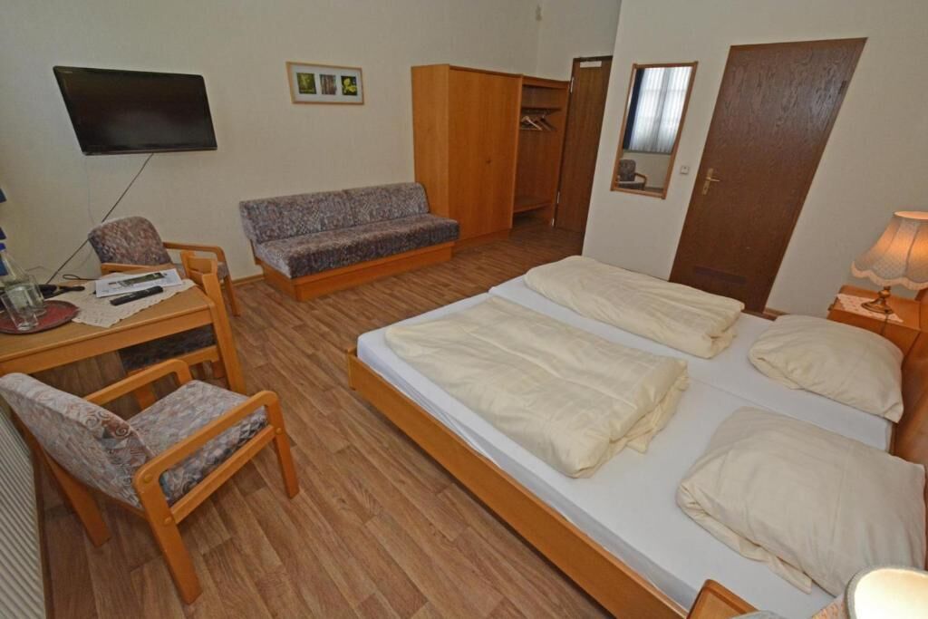 Un dormitorio con cama, sofá, escritorio y televisión.