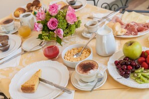 A breakfast table with various food items, including a slice of cake, a cup of coffee, a bowl of cereal, and a plate of fruits. - Hotel Trettenero (Recoaro Terme)