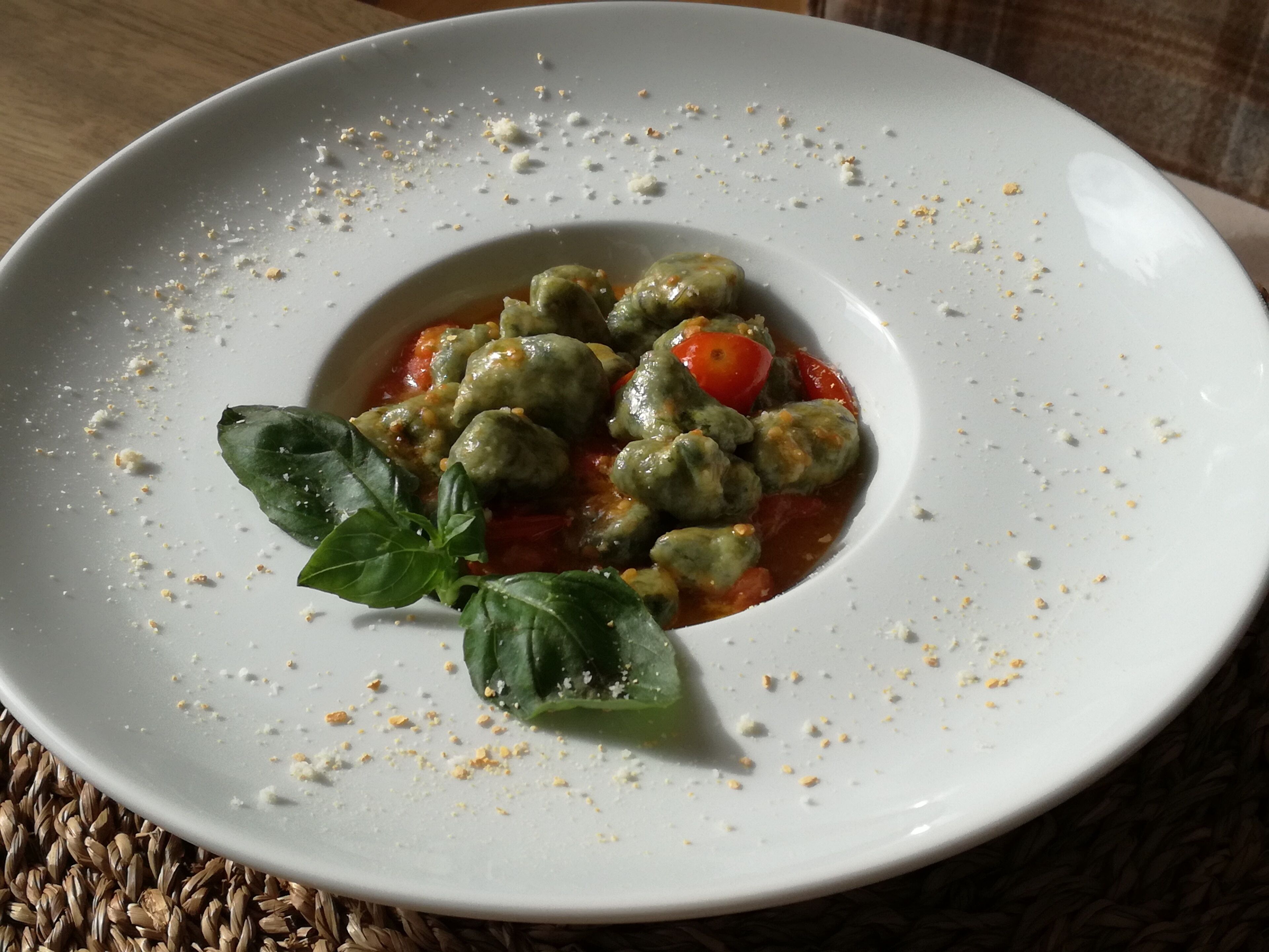 A plate of stuffed tomatoes with a basil garnish on a white plate.
