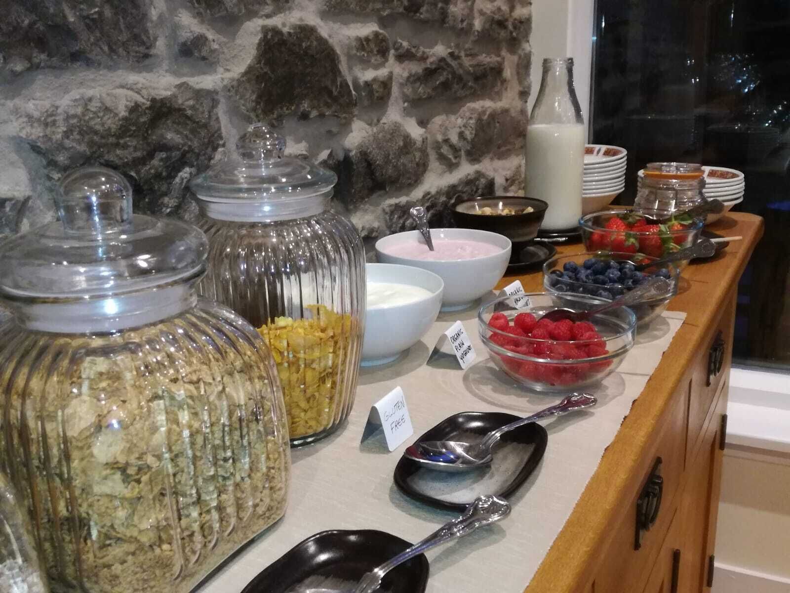 Un bufé con diversos alimentos, incluyendo yogur, bayas y granola.