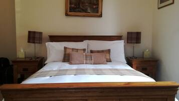 A neatly made bed with a wooden headboard, two bedside tables with lamps, and a painting on the wall.