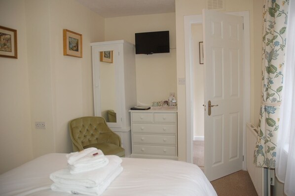 A bedroom with a bed, a chair, a dresser, a television, and a door. - Lubnaig Guest House (Callander)
