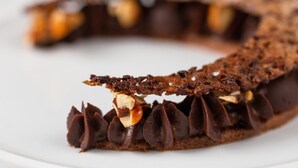 Une tarte au chocolat avec une pâte croustillante et une garniture onctueuse de ganache au chocolat, décorée de noix.