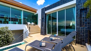 A modern outdoor pool area with lounge chairs and a staircase leading to an upper level.