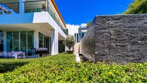 A modern building with a stone wall, a well-maintained hedge, and outdoor seating.