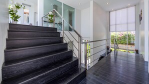 A modern staircase with dark wooden steps and metal railings, leading to a glass door.