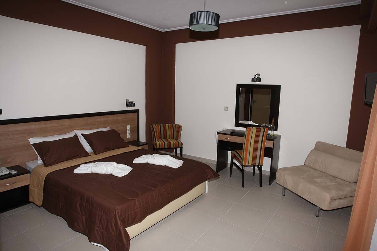 Una habitación de hotel con una cama grande, un escritorio, una silla y un sofá.