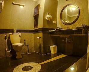 Een badkamer met toilet, wastafel, spiegel en handdoekrek.