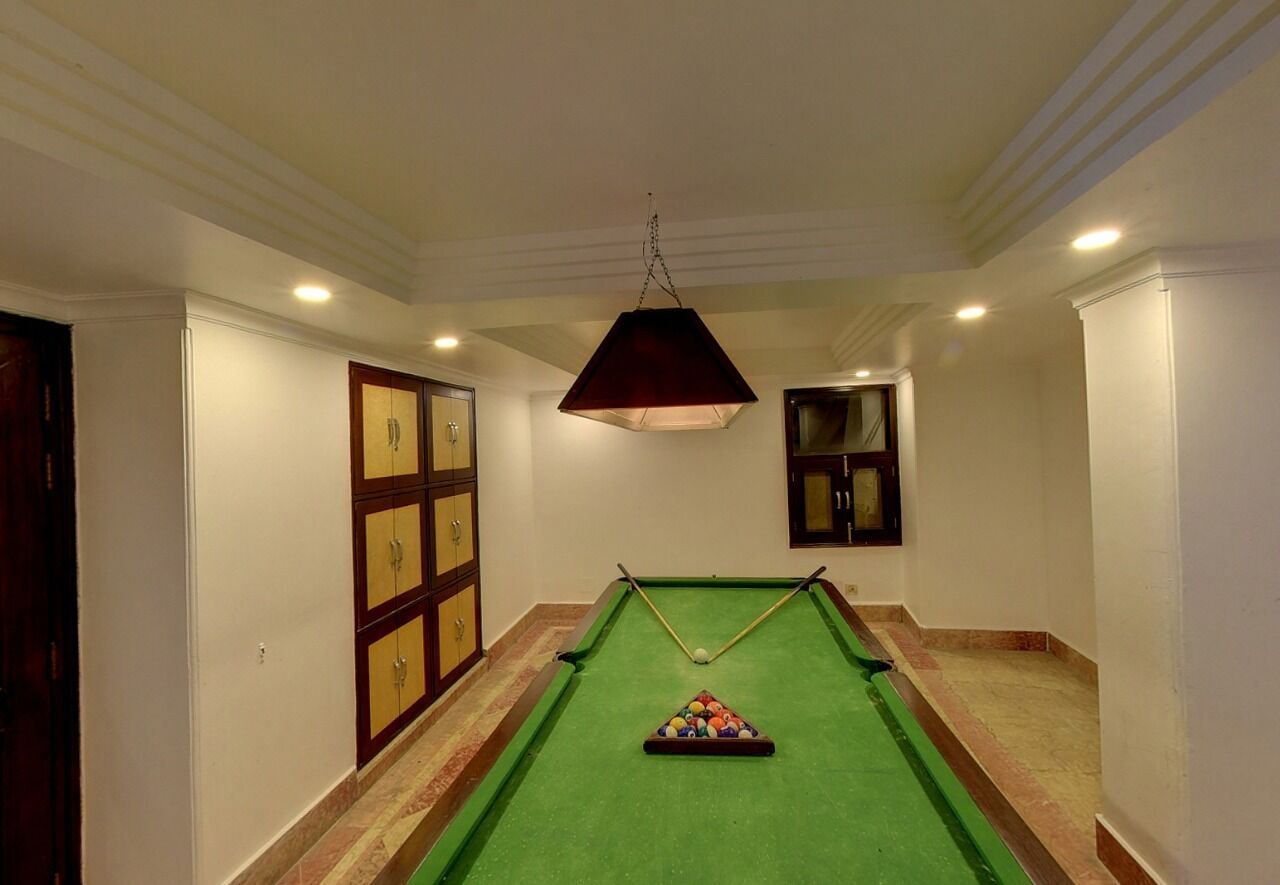 A pool table in a hallway with a hanging lamp, wooden cabinets, and a door with glass panels.