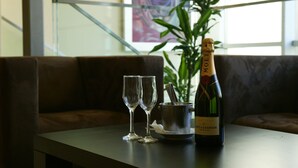 A bottle of Moët & Chandon champagne, two empty wine glasses, and a metal bucket on a table in a room with a large plant and a staircase in the background. - Hotel Contact (Belgrade)