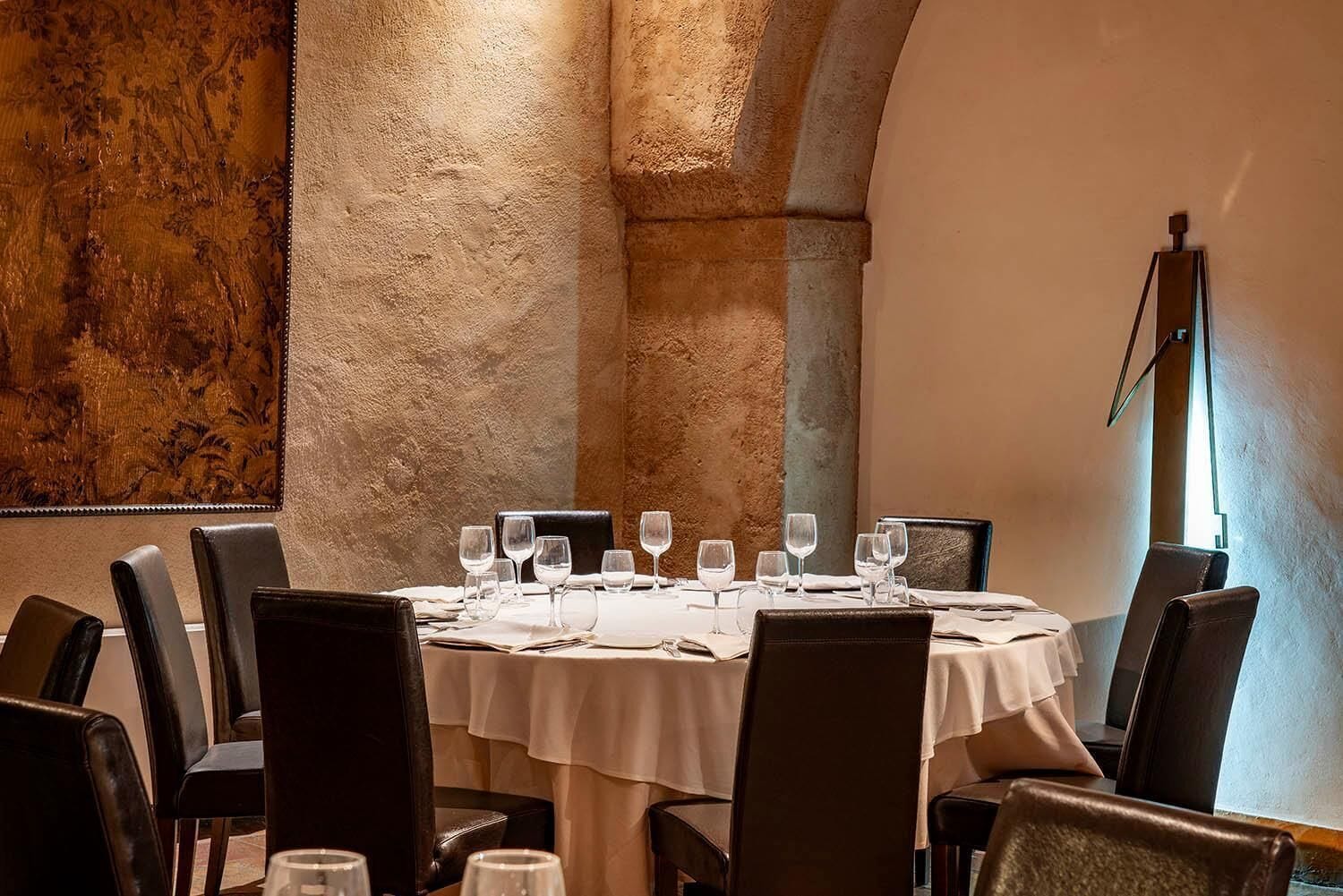 Un comedor con una mesa redonda dispuesta para cuatro personas, rodeada de sillas de cuero.