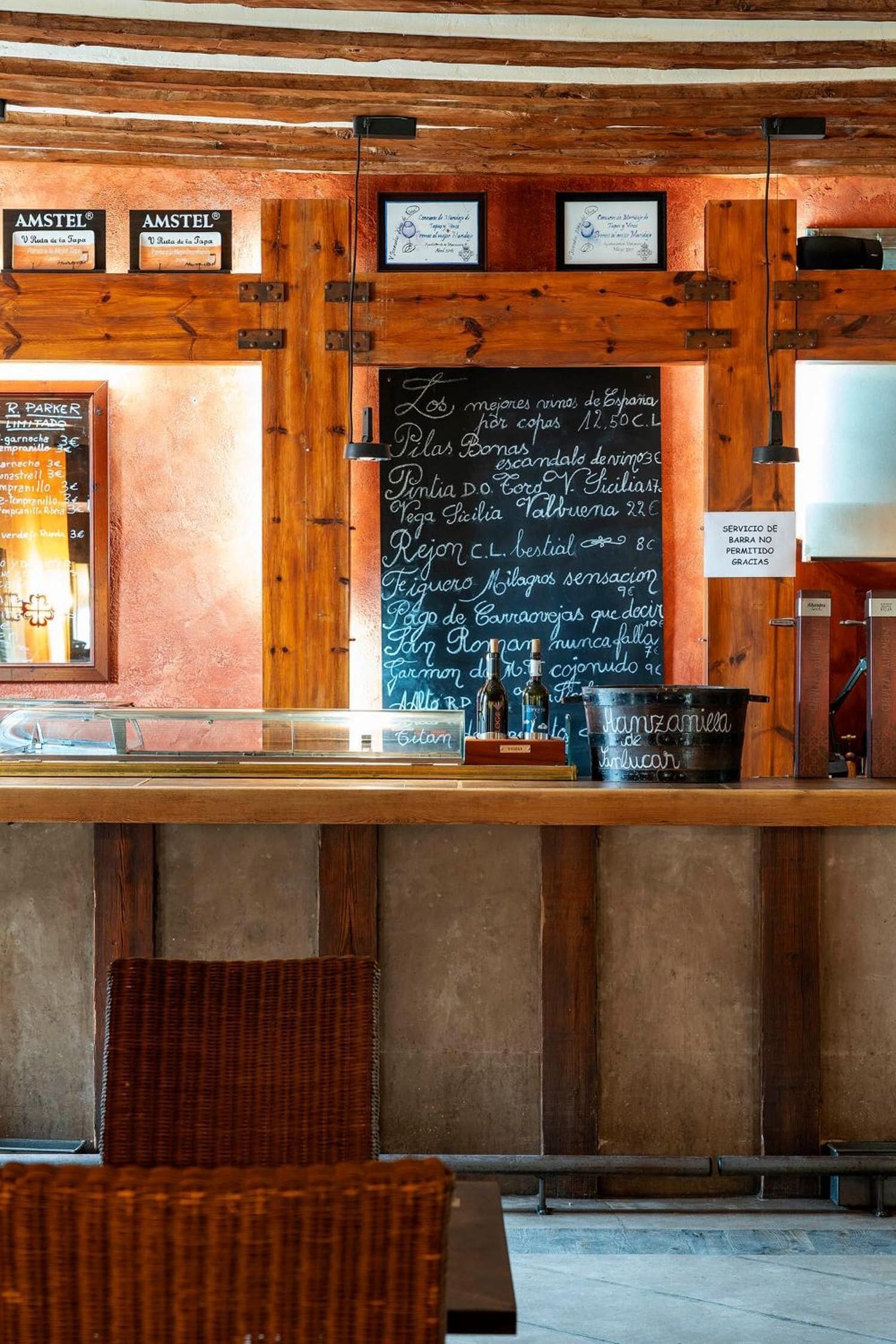 Un rústico área de bar con vigas de madera y un menú en una pizarra.