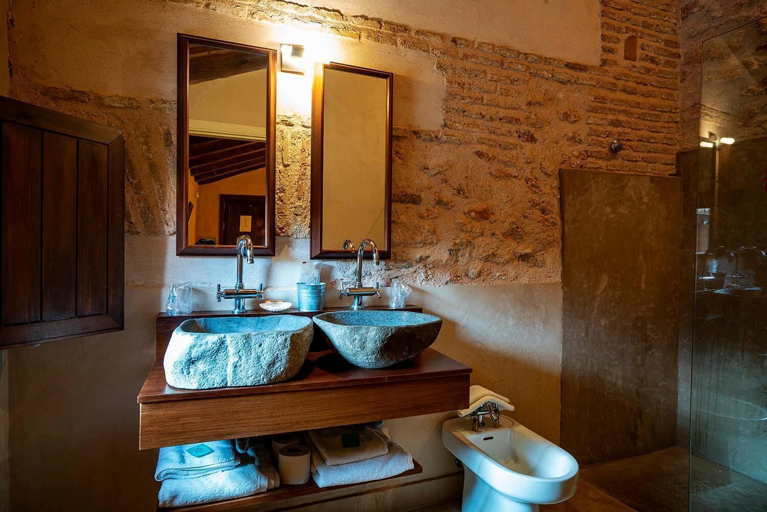Un baño con un lavamanos de piedra, un bidé y un espejo.