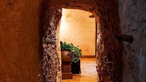 A narrow stone passageway leading to a room with a wooden floor and a potted plant. - Hotel Castillo de Pilas Bonas (Manzanares)
