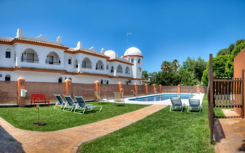 Un área de piscina con sillones reclinables y un edificio con techos abovedados.
