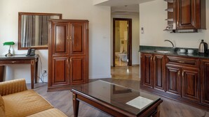 A spacious living area with a glass-top coffee table, wooden furniture, and a view into the kitchen area. - Christmas Hotel - Jerusalem (Jerusalem)