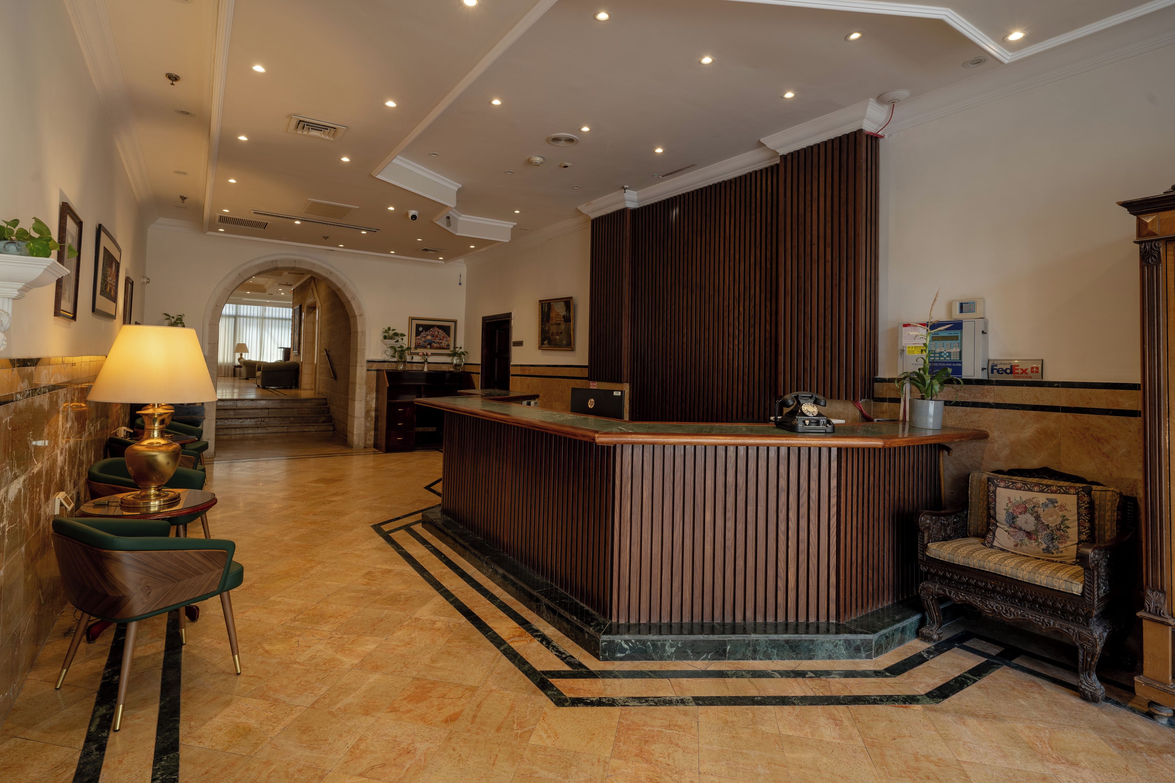 Un hall d’hôtel comprenant un comptoir d’accueil, un espace salon et un escalier menant à un autre étage.