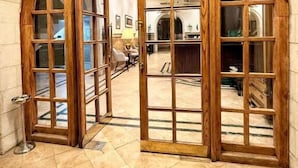 Un arco de entrada con paneles de madera y vidrios, que conduce a una habitación con suelo de baldosas y mobiliario.