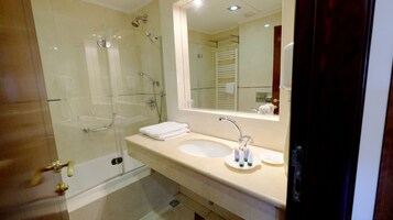 Un baño moderno con ducha envuelta en vidrio, lavamanos con espejo y un perchero para toallas.