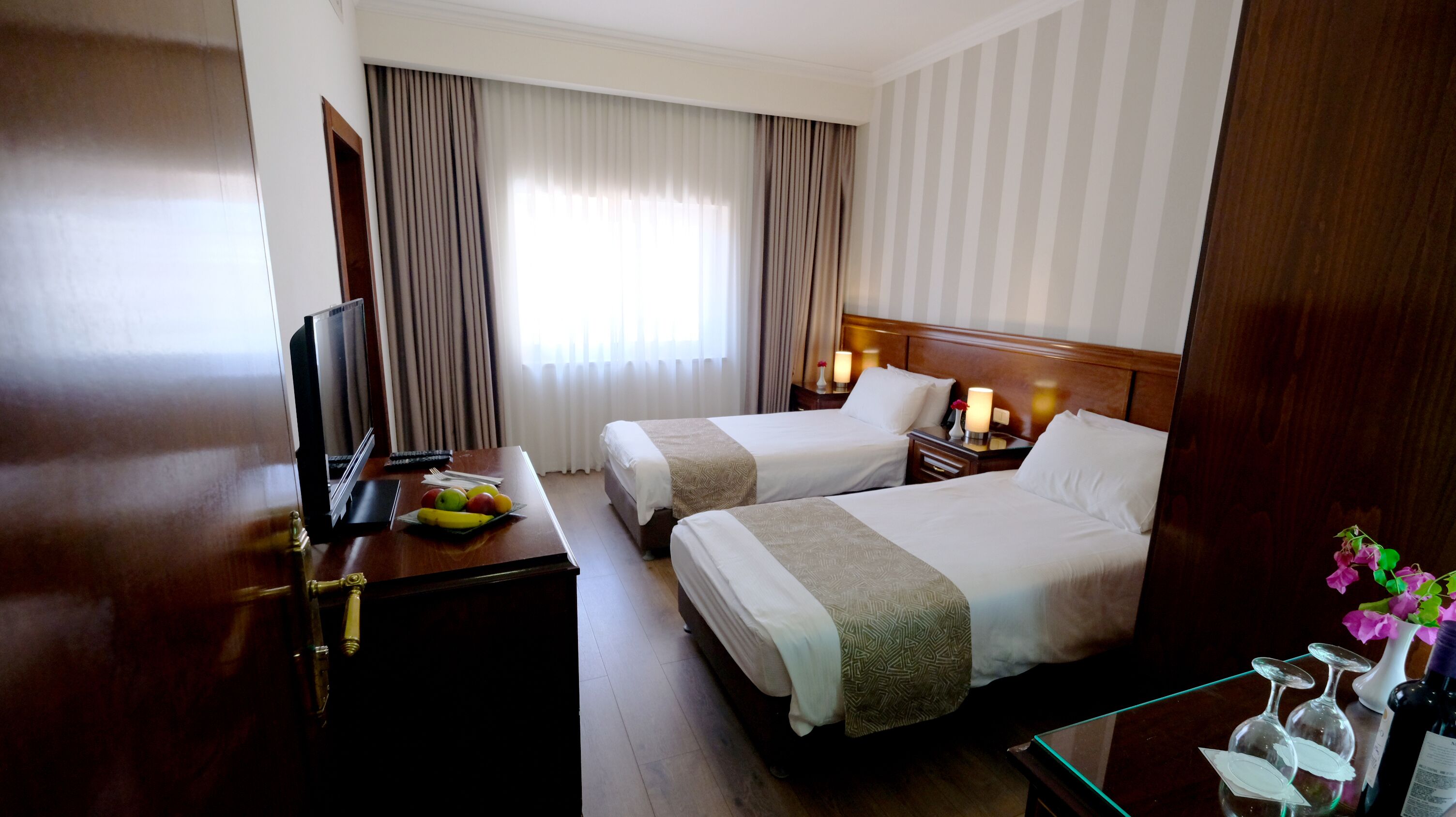 Een hotelkamer met twee bedden, een bureau met een televisie en een schaal fruit.
