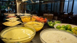 Un bufé con diversas opciones de comida, entre ellas frutas, verduras y salsas.