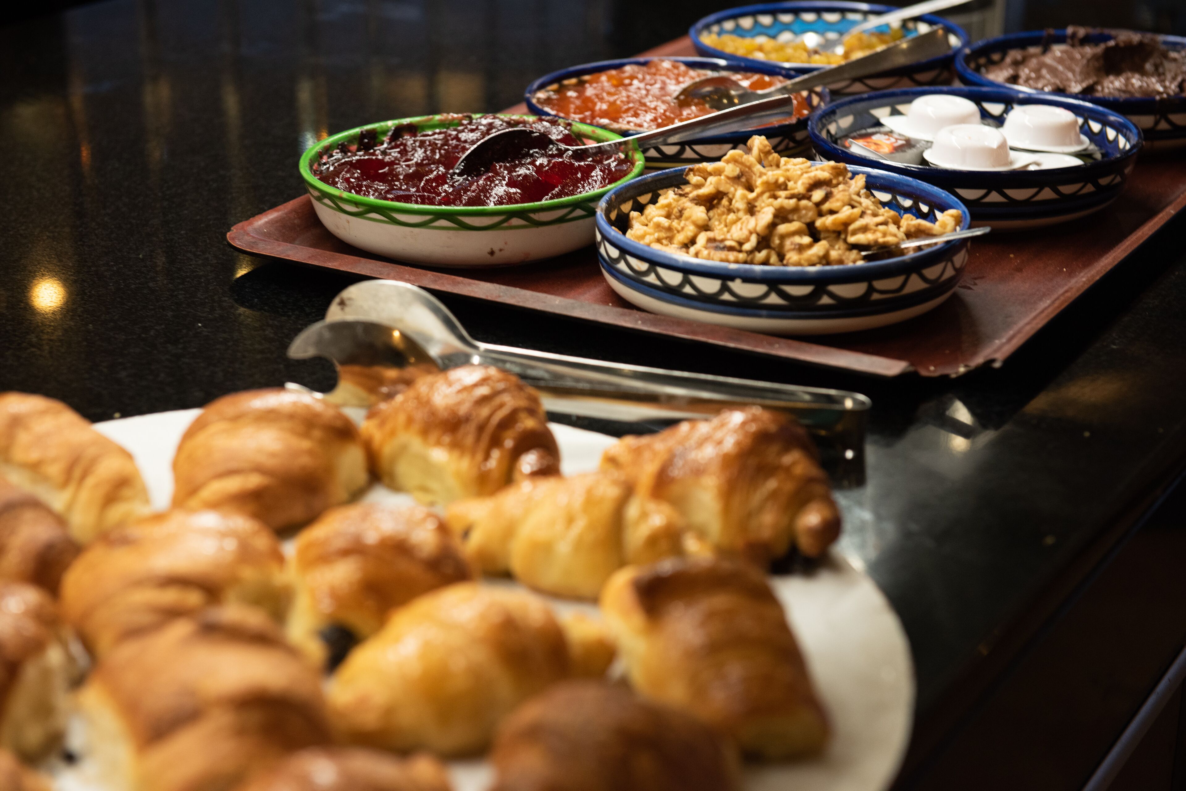 Een buffet met diverse gerechten, waaronder gebakjes en kommen met verschillende soorten eten.