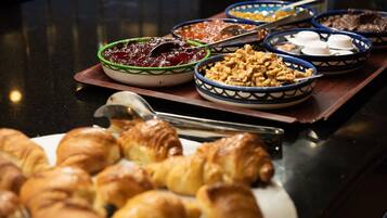 Een buffet met diverse gerechten, waaronder gebakjes en kommen met verschillende soorten eten.