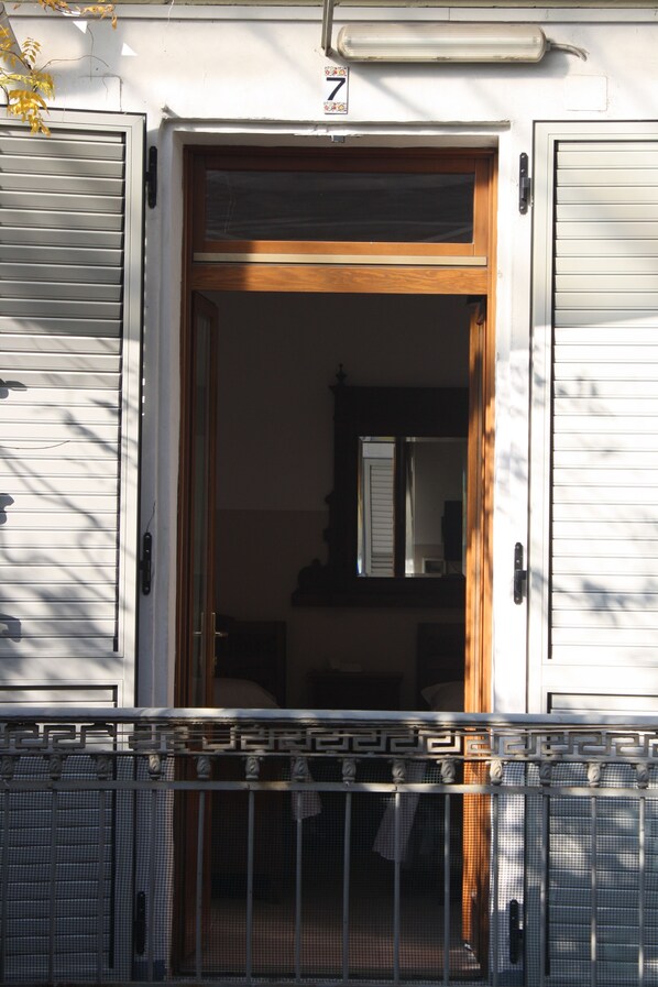 Una entrada de edificio con puerta de madera y portón de metal.