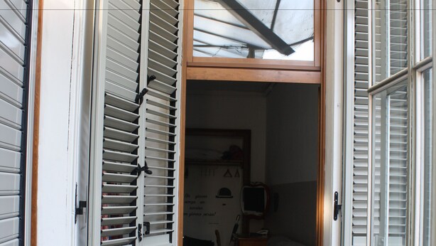 Un pasillo estrecho con un mostrador de madera y una puerta que da a una habitación con televisor y una silla.