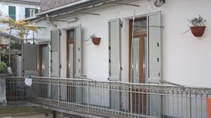 Un edificio con balcón, contraventanas y macetas.