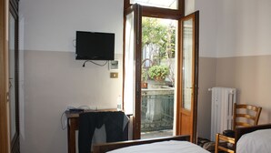 Habitación de hotel con cama, una silla, un televisor montado en la pared y ventana con vista al exterior.