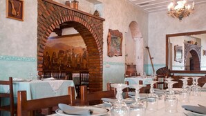 A restaurant with brick arches, wooden tables, and a mural on the wall. - Hosteria Peña Sagra (Cillorigo de Liebana)