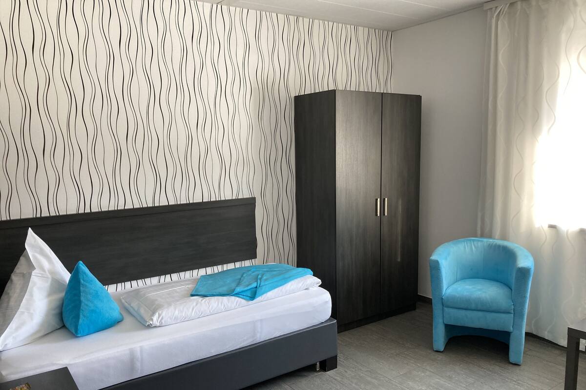A modern bedroom with a bed, a wardrobe, and a chair.
