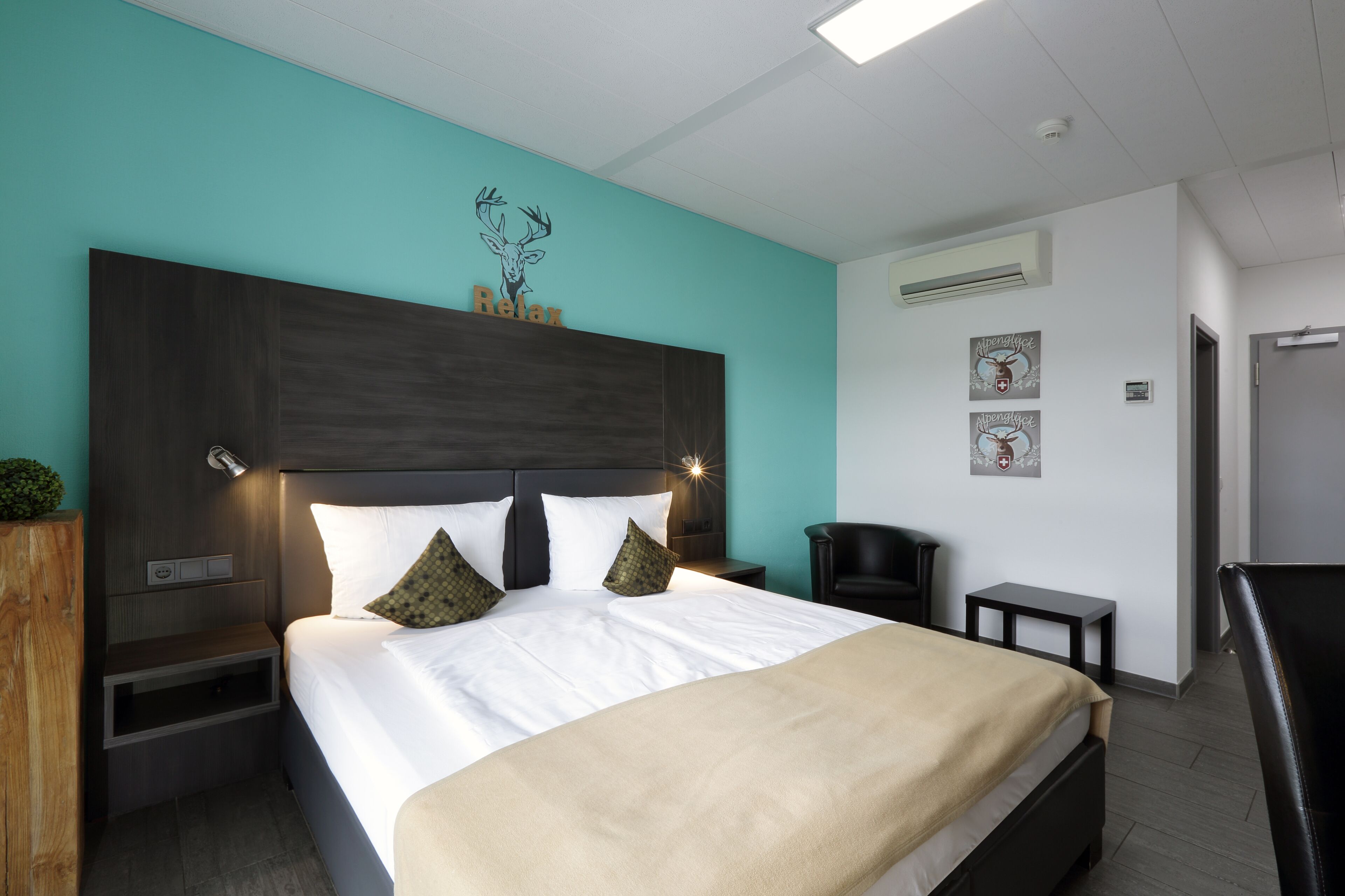 Moderni hotellihuone, jossa on suuri sänky, yöpöytä, työpöytä ja tuoli.