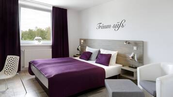 Un dormitorio moderno con una cama grande, una mesita de noche, una silla y vistas al exterior.