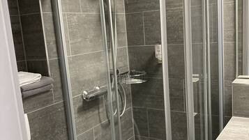 A modern bathroom with a glass-enclosed shower, a toilet, and a sink.