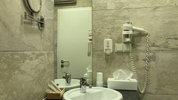 Un baño con dos lavabos, un espejo, un secador de pelo y una caja de pañuelos.