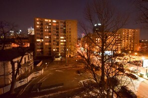 A nighttime view of a cityscape with tall residential buildings, a parking lot, and bare trees. - ShortStayPoland Srebrna - B36 (Warsaw)