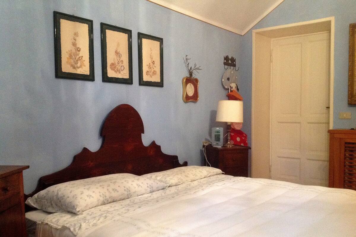 A bedroom with a wooden bed, a nightstand, a lamp, and three framed pictures on the wall.
